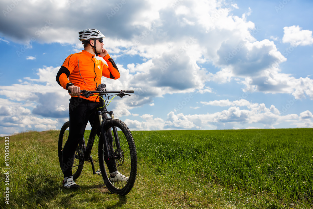 Young Cyclist In Orange Shirt Checks His Phone Young Cyclist In Orange Shirt Checks His Phone