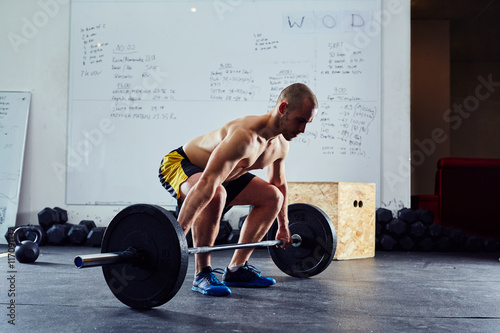 Young man doing power snatch exercise at gym