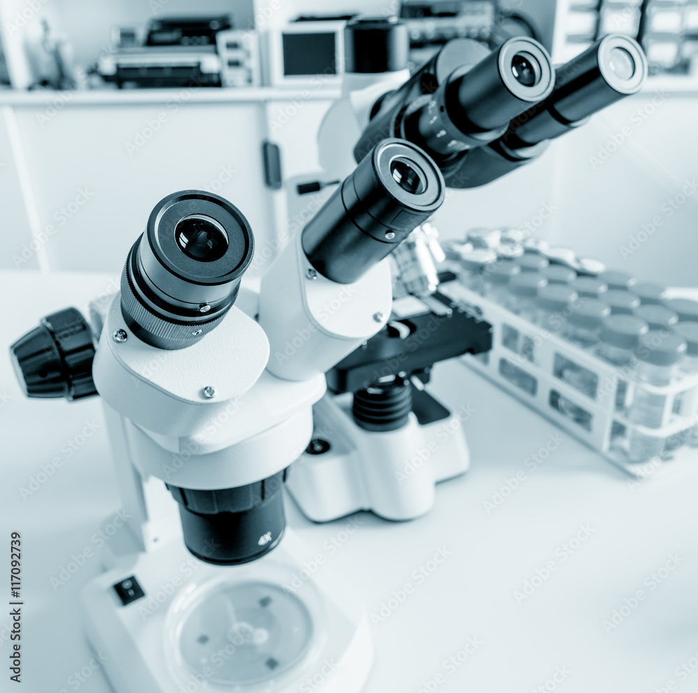 Science microscope on lab bench. Microbiology laboratory. Blue toned image of binocular microscope Science microscope on lab bench. Microbiology laboratory. Blue toned image of binocular microscope