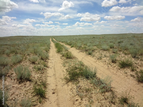 Infinite desert road in the Western Kazakhstan against a blue sky