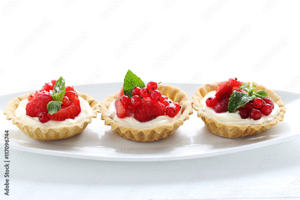 Dessert tartlets with berries on white wooden background Dessert tartlets with berries on white wooden background