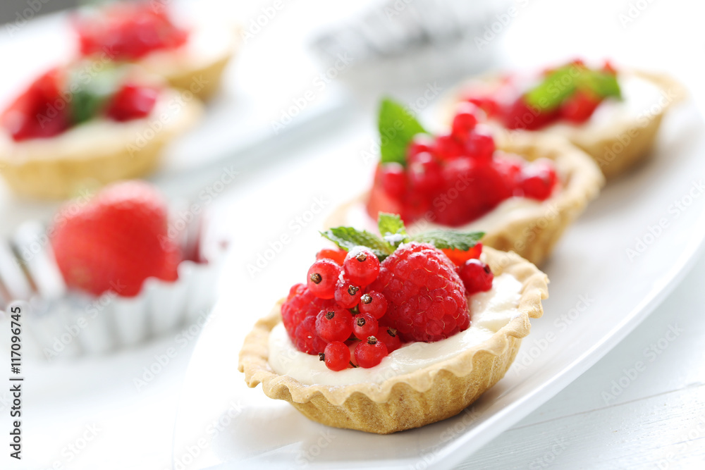 Dessert tartlets with berries on white wooden background Dessert tartlets with berries on white wooden background