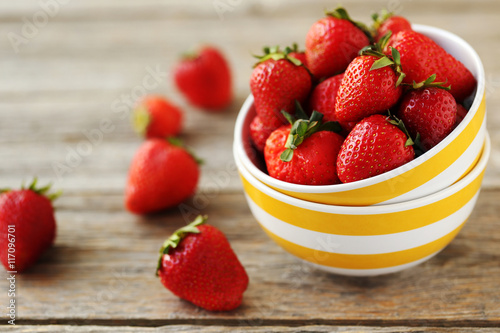 Fresh and tasty strawberries in bowl on a grey wooden table