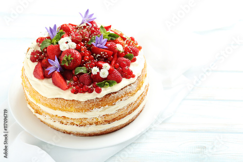 Billede på lærred Delicious biscuit cake with berries on blue wooden table