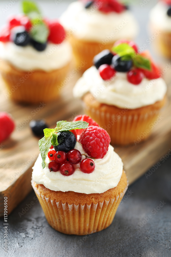 Tasty cupcakes with berries on grey table Tasty cupcakes with berries on grey table