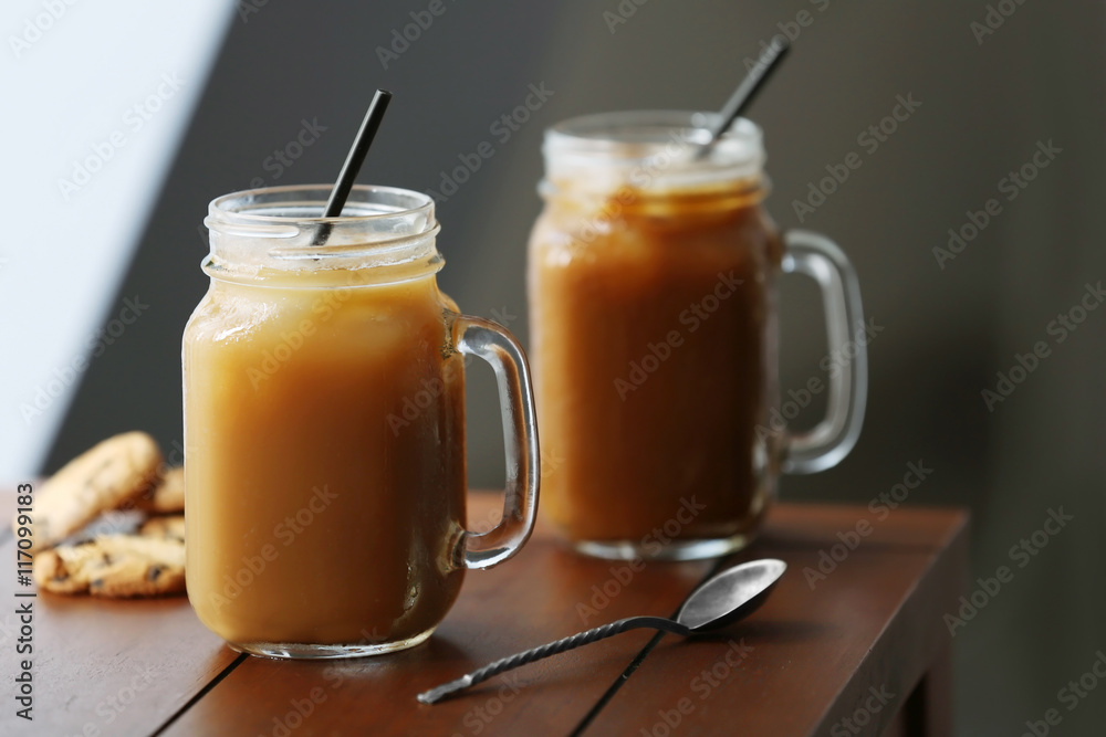 Iced coffee in glass jar with straw on brown wooden table Iced coffee in glass jar with straw on brown wooden table