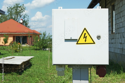 Power distribution wiring switchboard panel outdoor unit, distributing board compartment box, yellow high voltage warning triangle sign, large detailed isolated closeup