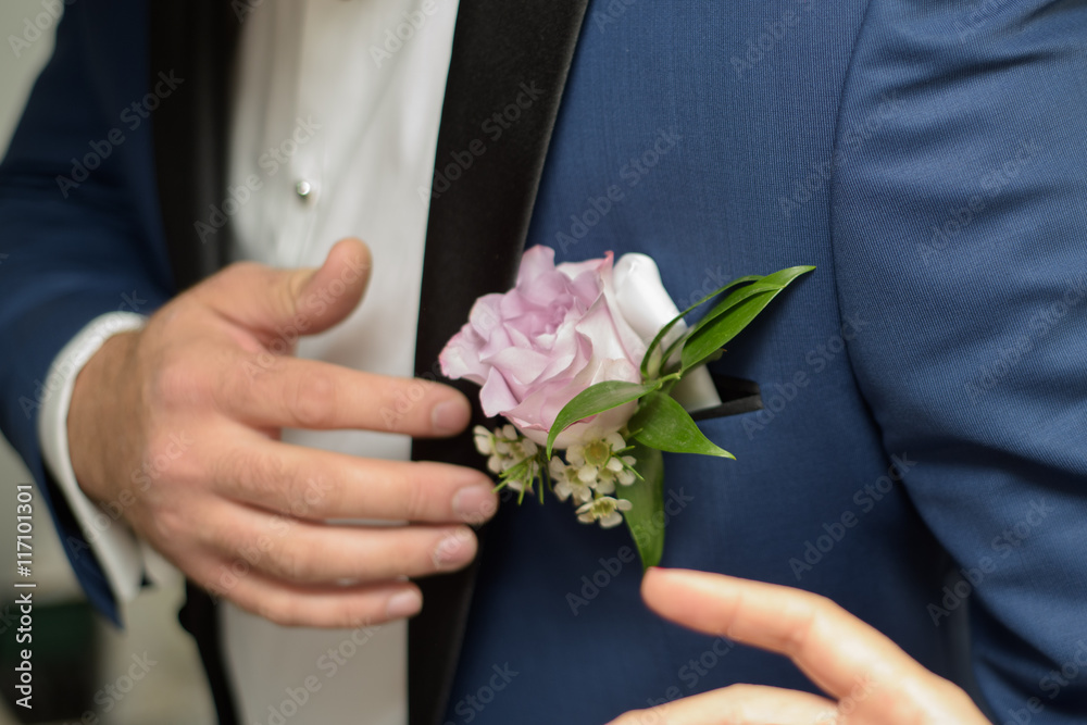 Groom arranging a rose to his boutonniere Groom arranging a rose to his boutonniere
