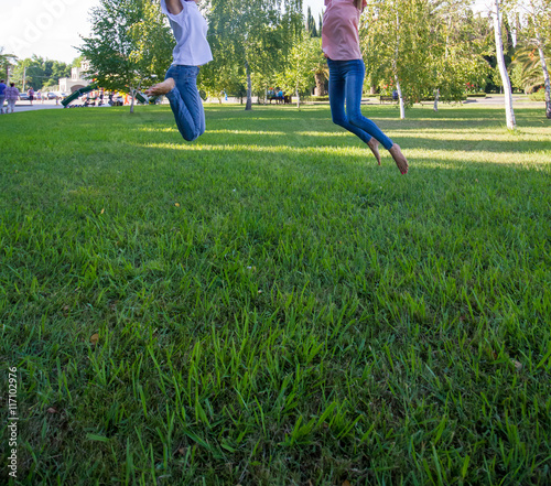  Two teen girl friends jumping on grass