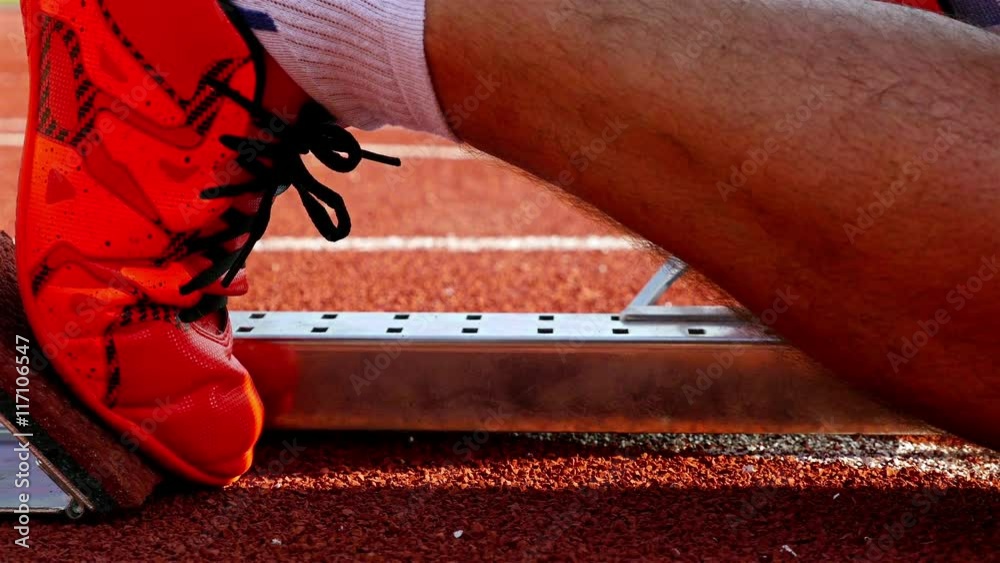 Single track and field sprinter in a stadium starting out of the block