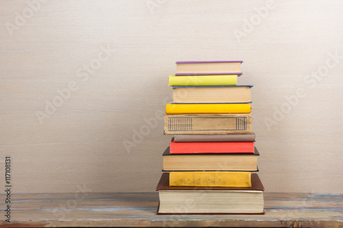 Books on grunge wooden table desk shelf in library. Back to school background with copy space for your ad text. Old hardback books with no labels, blank spine