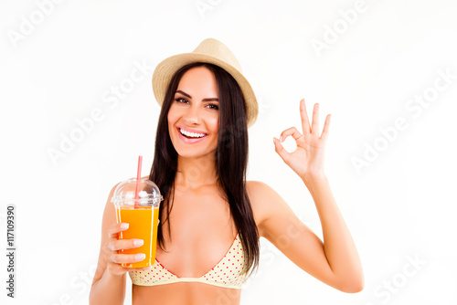 Happy woman in bikini and hat holding cocktail and gesturing "OK