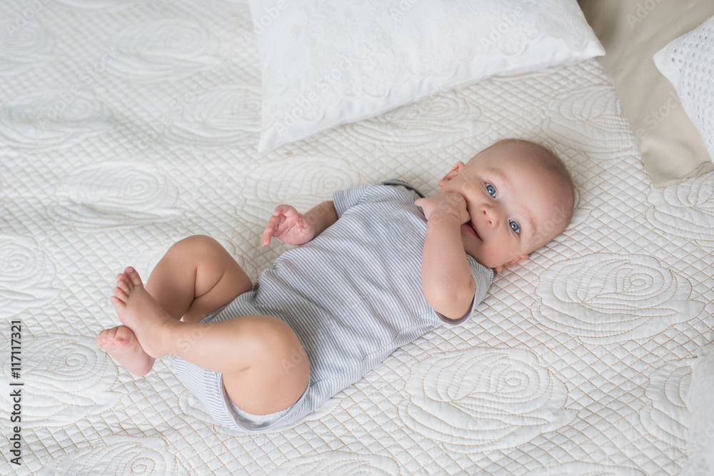 Infant in a grey baby clothes on a bed Infant in a grey baby clothes on a bed