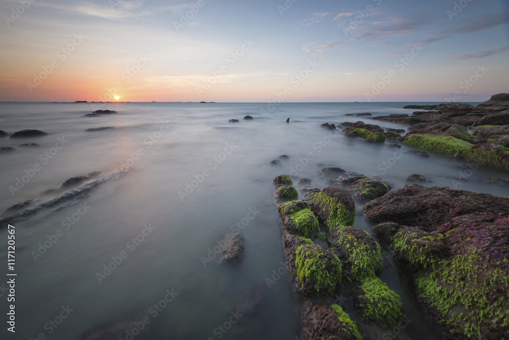 Beautiful sunset decorated with waves and mosses stone
