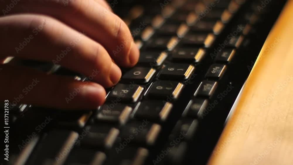 Black Keyboard Typing Side View. The camera trucks along a close up of fingers typing on a black computer keyboard.