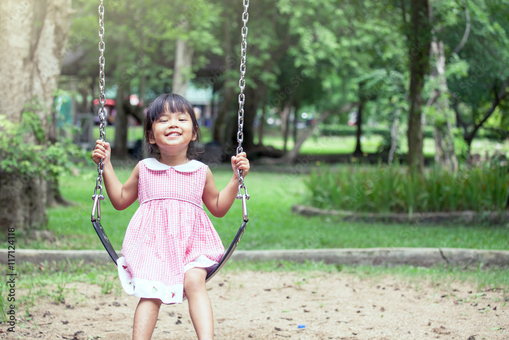 Child asian girl having fun to play swing in playground