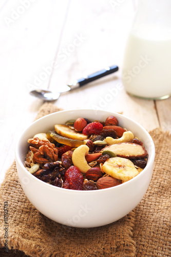 A healthy bowl of muesli mixed with dried fruit and nuts on a sackcloth.