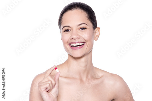 Attractive unclad woman holding a capsule