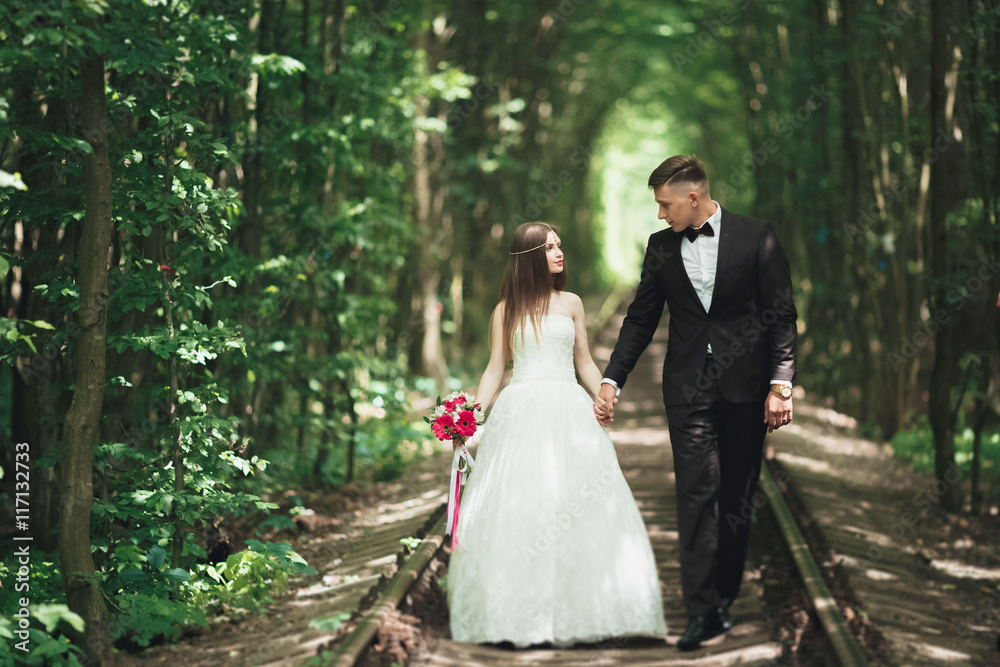 Happy wedding couple charming groom and perfect bride posing in park