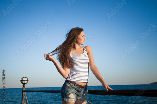 Girl standing on the pier . Beautiful sea background