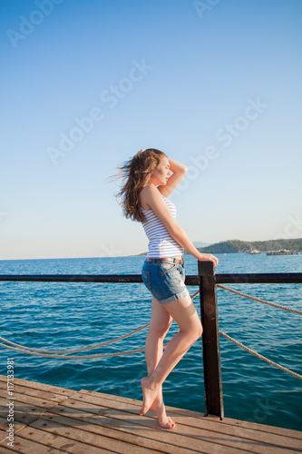 Girl standing on the pier . Beautiful sea background © stacestock