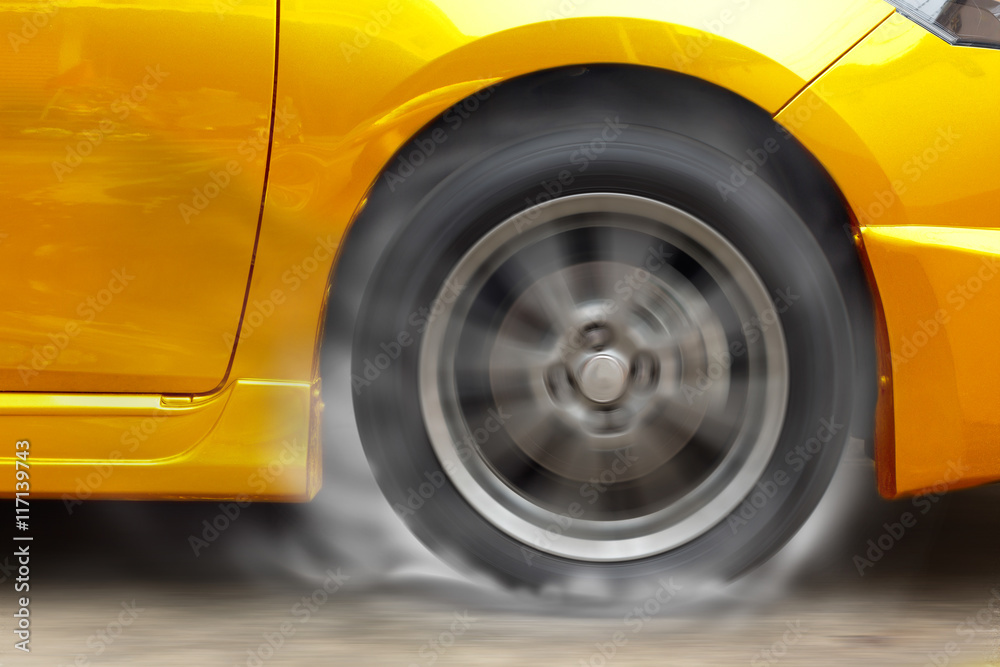 Gold car racing spinning wheel burns rubber on floor.