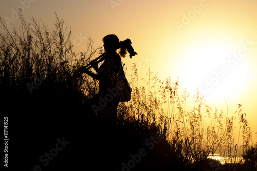 silhouette of a young woman traveling in the throwing shoulder on professional photographic tripod