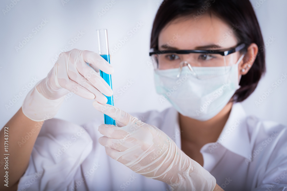 Scientist looking at blue test tube in the laboratory.