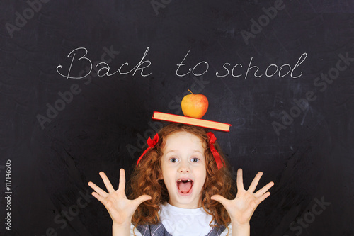 Laughing girl with a book and an apple on his head. Easy learnin photo