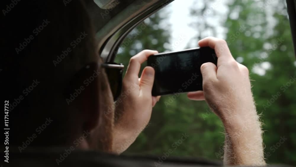Back view of young couple driving in car and taking photos of road with smartphone Back view of young couple driving in car and taking photos of road with smartphone