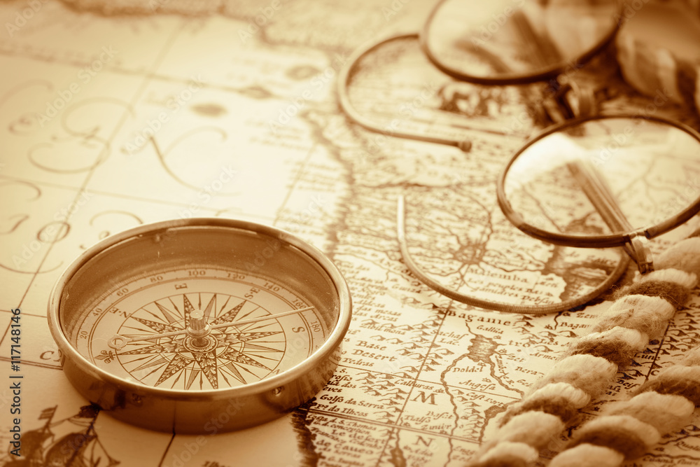 antique compass and glasses on vintage map background