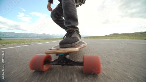 Guy on his longboard skate. Close up of longboard and foot. Side view. Tracking shot photo