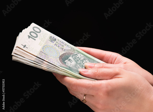Close up of female hand holding Polish money banknotes against dark background