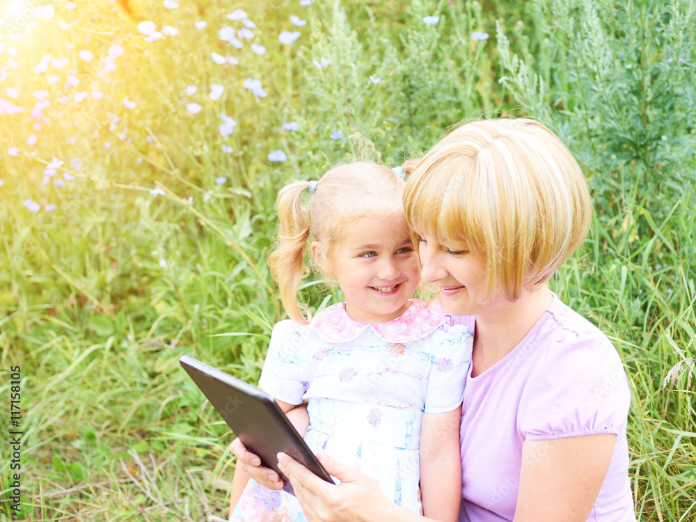 Happiness mom and daughter web surfing using tablet outdoors on Happiness mom and daughter web surfing using tablet outdoors on