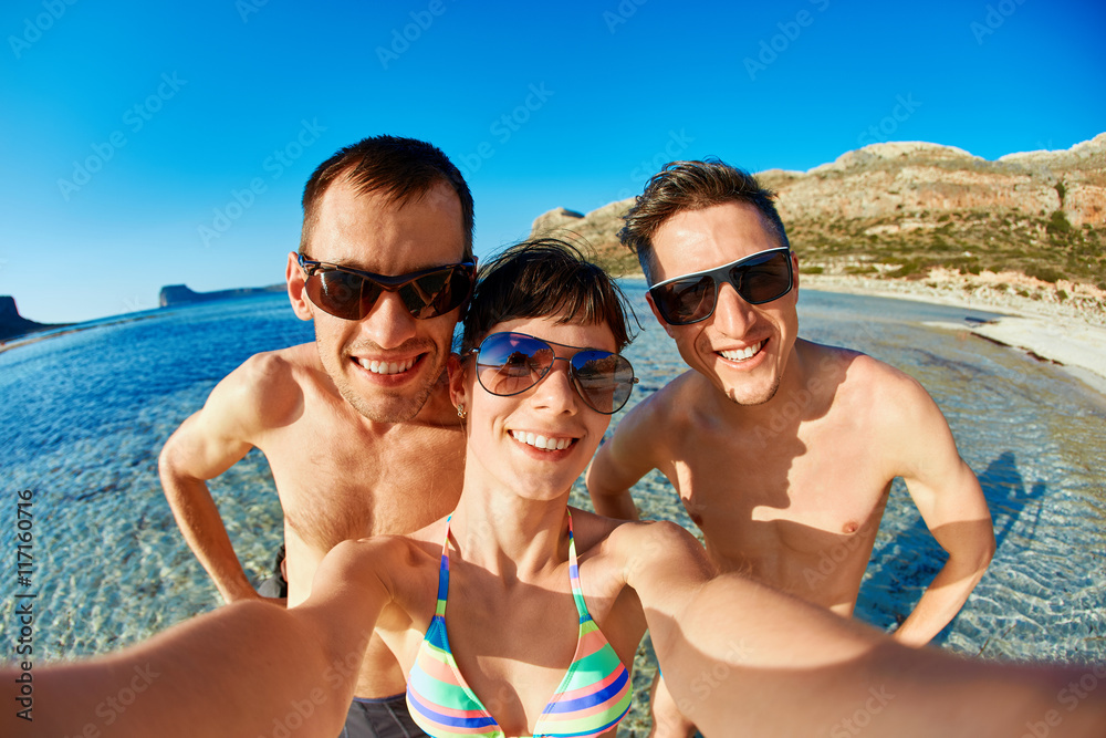 young happy couple friends on the beach taking selfie on sea background. Balos beach, Crete, Greece.