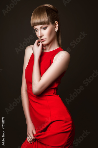 beautiful woman model posing in simple elegant red dress in the studio on black background