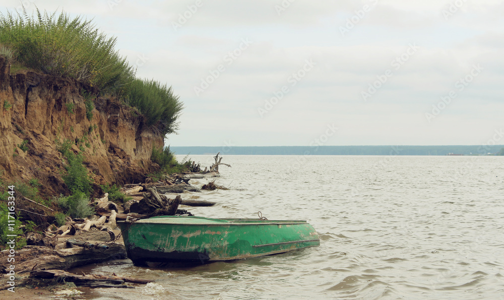 Old green boat with oars on the coast