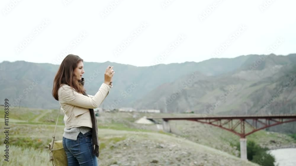 Young person relaxes on hiking in mountains and taking photo with mobile phone Young person relaxes on hiking in mountains and taking photo with mobile phone