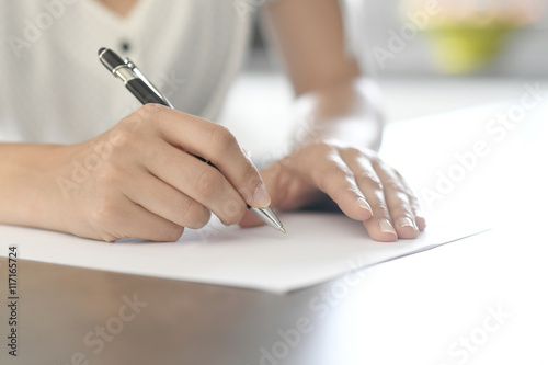 Closeup of woman's hand writing on paper with pen photo