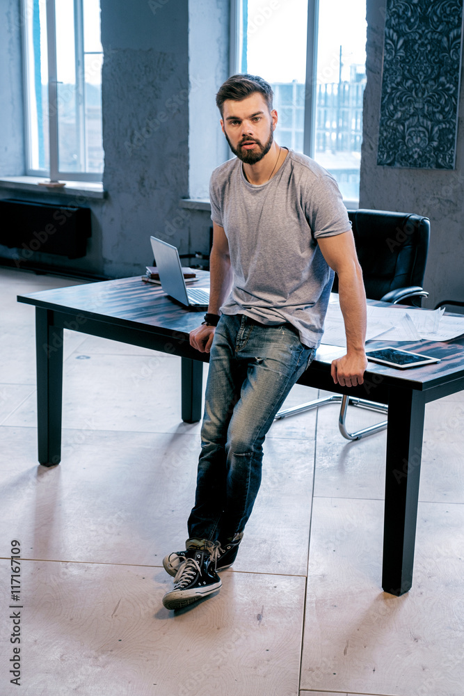 Good-looking man leaning on desk in office Stock Photo | Adobe Stock