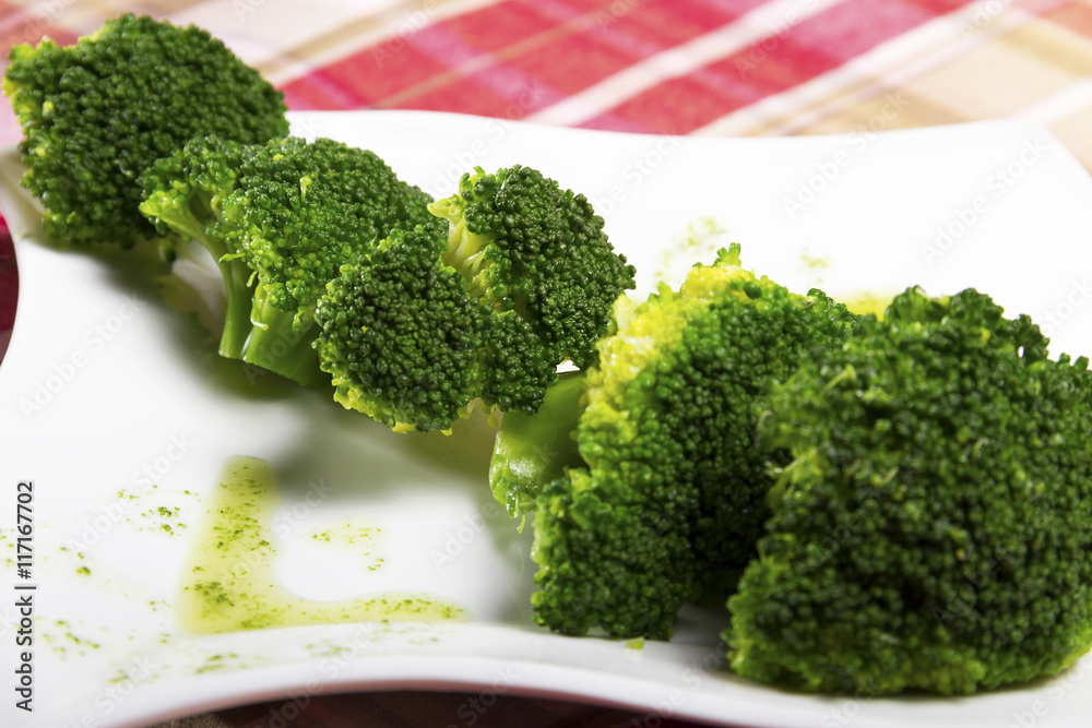 Salad - green, cooked and seasoned broccoli on a white plate served on the table. Salad - green, cooked and seasoned broccoli on a white plate served on the table.