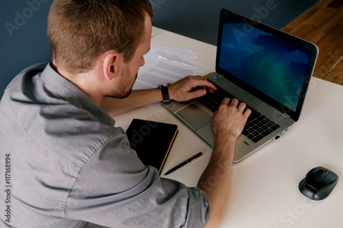 Overshoulder of businessman using laptop at work photo