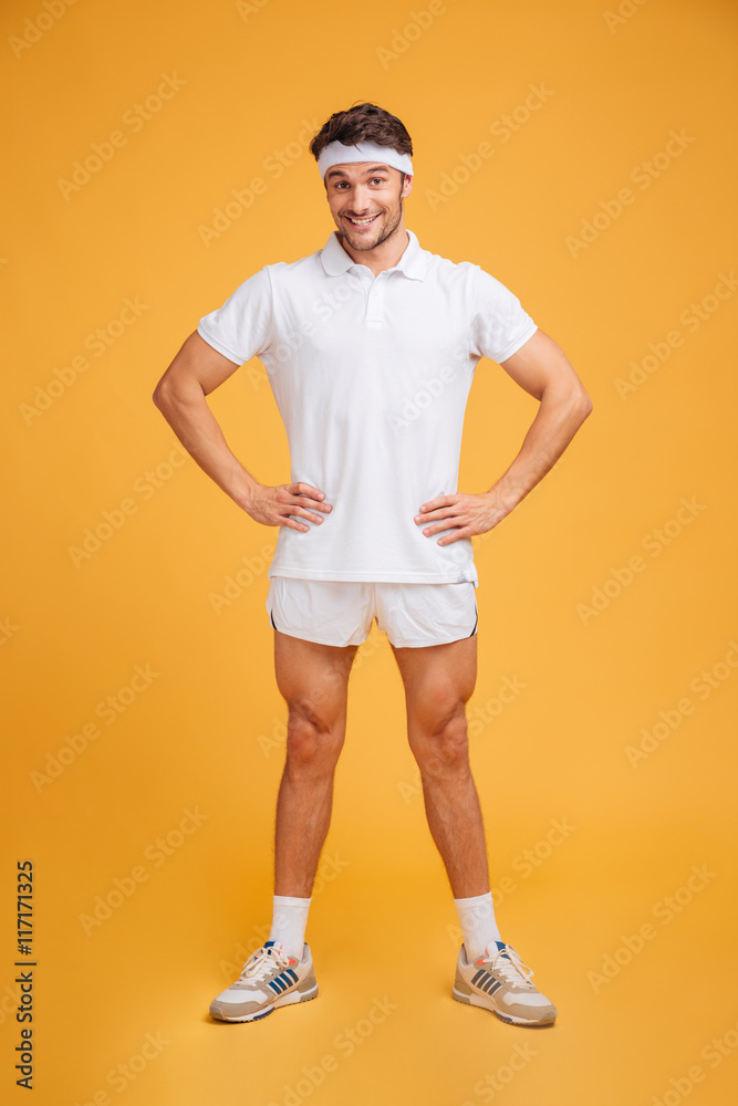 Joyful amusing young sportsman standing with hands on hips Joyful amusing young sportsman standing with hands on hips