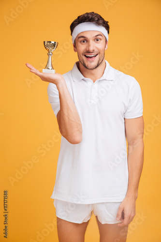 Portrait of happy young sportsman holding trophy cup