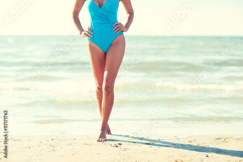 close up of woman in swimsuit walking on beach