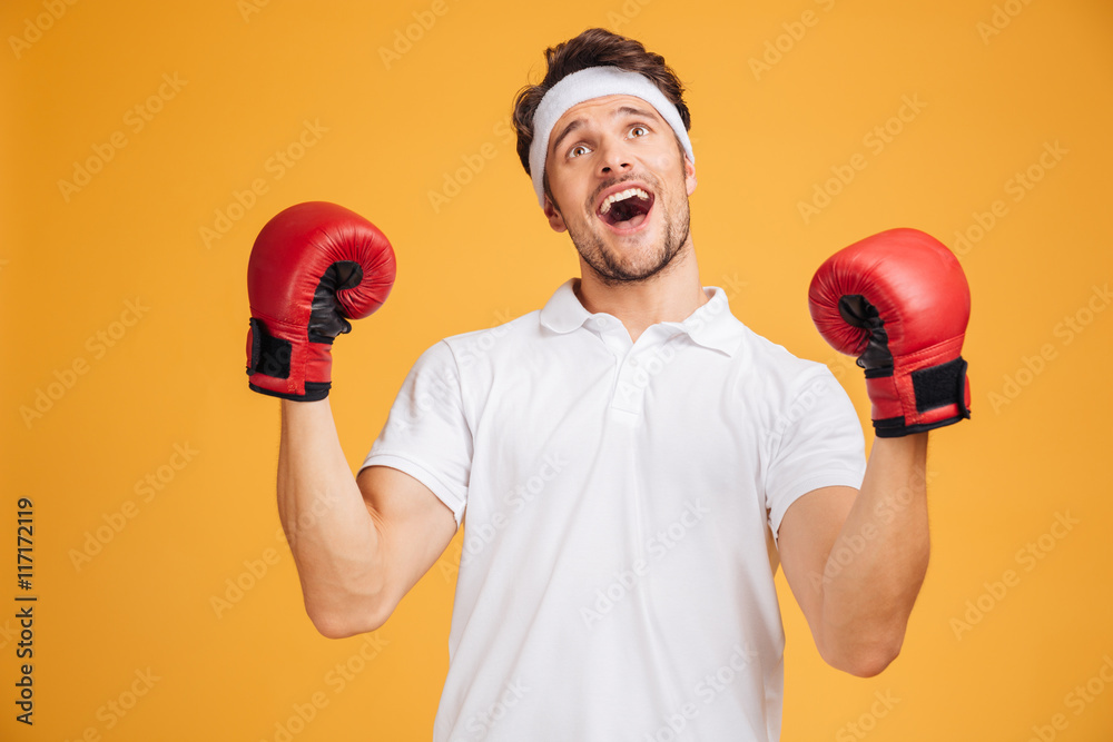 Cheerful excited man boxer in gloves shouting and celebrating success Cheerful excited man boxer in gloves shouting and celebrating success