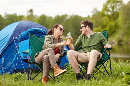 happy couple clinking drinks at campsite tent