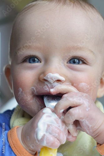 Close up portrait of happy baby eating yohurt photo