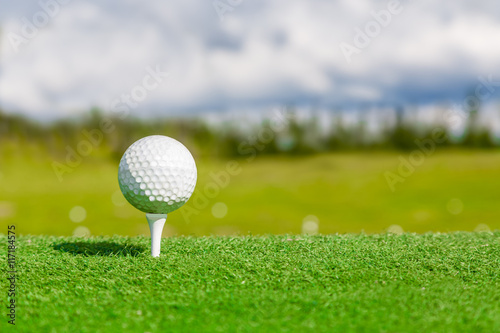 Close up of golf ball and tee with with blurred background.