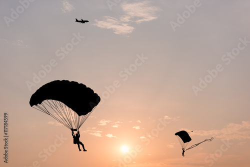 Valokuva Silhouette of parachute and airplane on sunset background